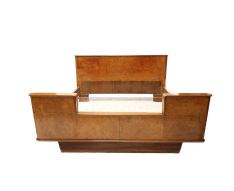 A French Art Deco burr walnut bedroom suite,each piece inset with pink-tinted glass tops, comprising:a pair of bedside cupboa