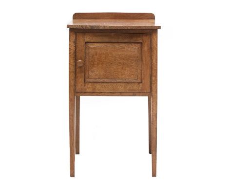 A Cotswold School oak bedside cupboard,with a bow front and panelled door with a carved octagonal handle,44cm square74cm high