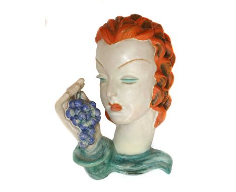 A Goldscheider pottery wall mask,no. 7527/5, modelled as a lady holding a bunch of grapes, with orange hair and lips, turquoi