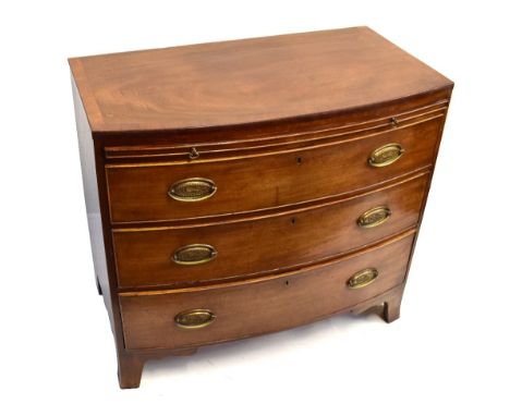 A George IV mahogany and crossbanded bowfronted chest of drawers with brushing slide above three long graduated drawers on sp