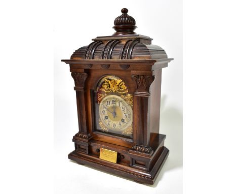 JUNGHANS; a late 19th century carved walnut mantel clock, the brass face with applied gilt detail and silvered circular dial,