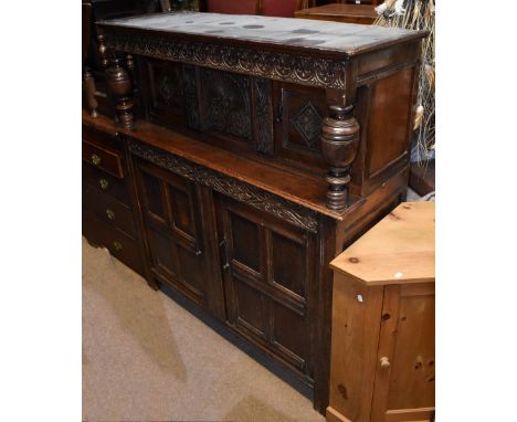 A late 17th century oak court cupboard with carved frieze above substantial ring turned uprights, twin cupboard upper doors a