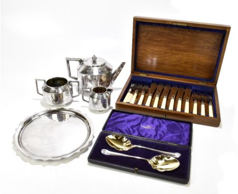 A group of electroplated items comprising a three piece floral, scroll and swag decorated tea set, the teapot with ivory insu