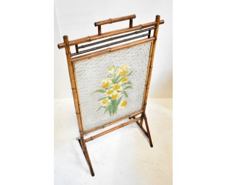 An Aesthetic Movement bamboo framed firescreen, the moulded glass panel with painted floral detail, on metal feet, height 101