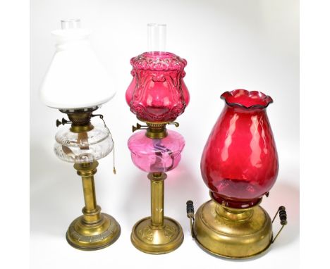 Three 19th century brass oil lamps, the first with tapered milk glass shade and clear reservoir, the second with foliate reli