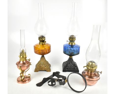 Four late 19th/early 20th century oil lamps, the two larger with orange and blue glass reservoirs and stamped 'Falk's British