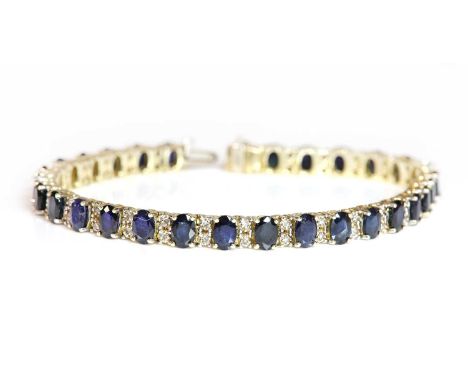 A Continental sapphire and diamond line bracelet,with a row of oval mixed cut sapphires, all four claw set across the width o
