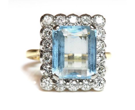 An aquamarine and diamond rectangular cluster ring,with a central emerald cut aquamarine, four claw set at the cut corners. A