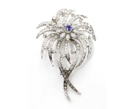 A sapphire and diamond spray brooch, c.1950,with a central flower head cluster composed of a circular mixed cut sapphire with