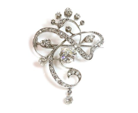 An Art Nouveau diamond set brooch/pendant, c.1890,of scrolling whiplash form. A cushion cut diamond, estimated as approximate