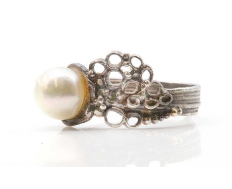 * A sterling silver single stone cultured pearl ring, by Gerda Flockinger,with a 6.60mm cultured pearl, peg set to a molten e