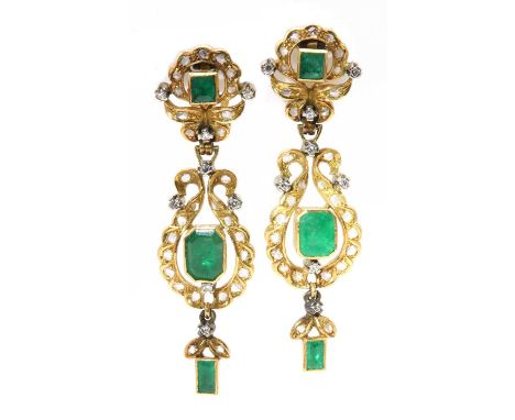 A pair of gold emerald and diamond drop earrings, an emerald cut emerald rub set to a plain collet, with a scroll frame grain