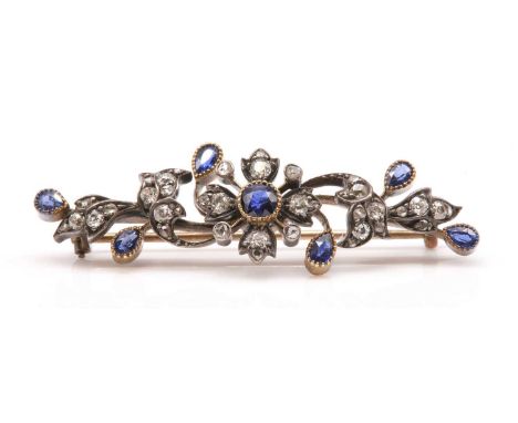 A late Victorian sapphire and diamond spray bar brooch, c.1890,with a central flower head cluster. A circular old mixed cut s