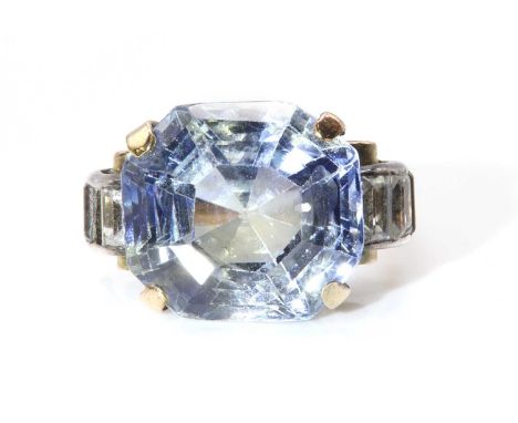 A single stone sapphire ring with white sapphire set shoulders, c.1940,with an octagonal step cut part coloured sapphire, est