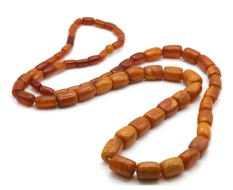A single row graduated amber barrel shaped bead necklace,17.70 to 17.50mm in size, strung plain to a circular bead at the bac