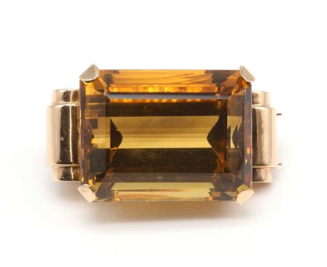 An odeonesque rose gold single stone citrine clip brooch, c.1940,with an emerald cut citrine, four claw set to a pierced coll