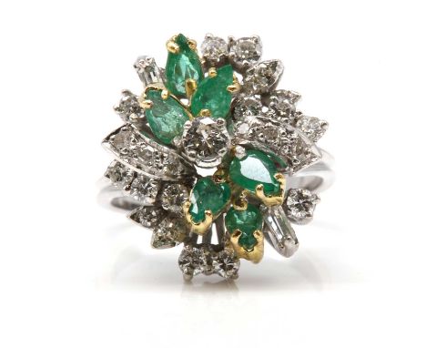 A diamond and emerald spray style cocktail ring,with a brilliant cut diamond, four claw set at the centre. A spray of pear cu