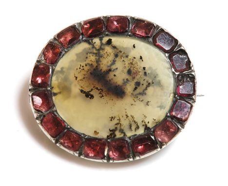 A Georgian silver picture agate and garnet brooch,with an oval agate plaque, with a border of flat cut garnets, damaged. 29 x