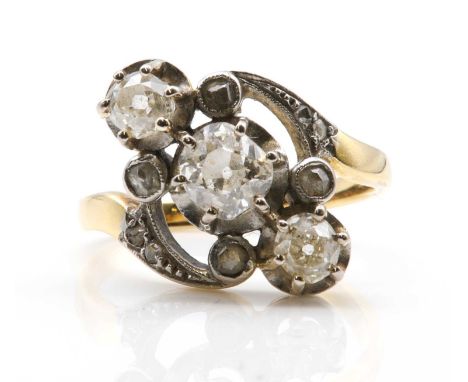 A French Art Nouveau three stone diamond crossover ring,with an old European cut diamond, six claw set to a white scalloped c