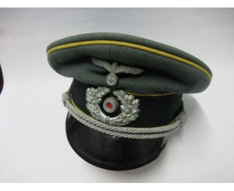 A Third Reich style visor cap, in green wool fabric, with yellow piping and dark green felt hat band, silver coloured braid, 