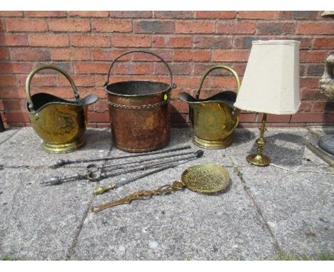 Two brass helmet shaped coal scuttles, a candlestick lamp, copper log bin, irons, etc.
