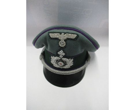 A Third Reich style visor cap, in green wool, with violet coloured piping and silver braid, dark green band with silver threa