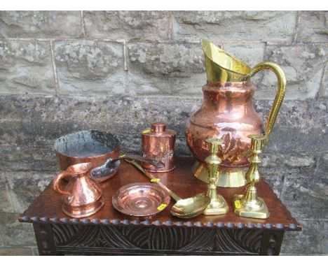 A collection of copper and brass to include a large jug, pair of candle sticks, a ladle, dish, pan, tea caddy and jug
