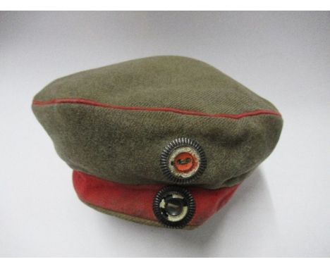 An Imperial German army style beret, in khaki with red headband and piping, with two metal cockade buttons to the front, havi