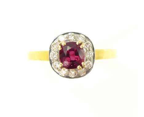 An unheated ruby and diamond cluster ring the central, cushion cut ruby weighing approximately 1.1cts, surrounded by twelve r