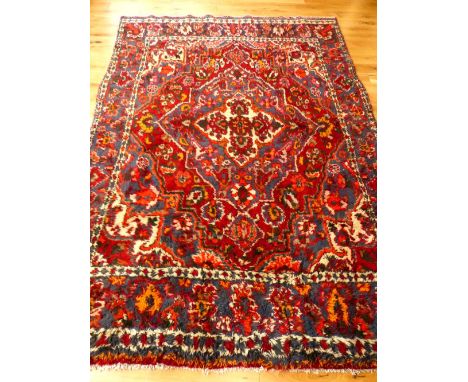 Persian carpet,quattrefoil medallion to centre within tear-drop medallion, overall with floral design over red, cream and ind