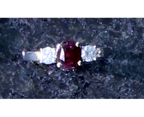 An unheated ruby and diamond three stone dress ring the central, oval cut ruby weighing approximately 1.4cts, flanked by two 