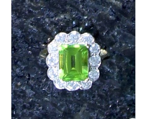 A peridot and diamond cluster ring in 18ct yellow gold, the central, emerald cut, claw set peridot, weighing 3.75ct, surround