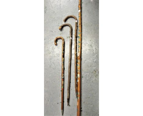 Four various alpine canes, applied with various enamel decorated shields 