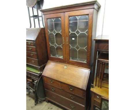George III oak bureau bookcase, the moulded cornice above two lead glazed doors with pull-out candle slides, the base with fa