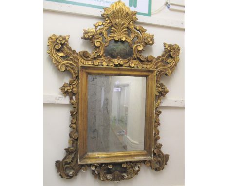 20th Century Continental carved and gilded cartouche mirror, the shaped surmount with a central painted landscape, 44ins x 32