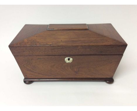 Regency rosewood tea caddy, of sarcophagus form with flanking drop ring handles on squat bun feet, hinged cover enclosing twi