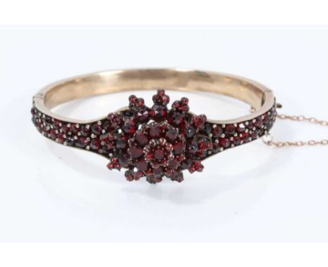 Late 19th century Bohemian garnet hinged bangle with a flower head cluster on pavé set band in gilt metal setting. Cluster ap