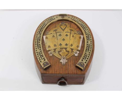 A late Victorian oak and brass mounted cribbage board in the form of a horseshoe, the top with an applied panel of three card