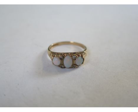 A 9ct gold and three stone opal ring, interspersed with white stones, approx 2.6 grams, size M, generally in good condition, 