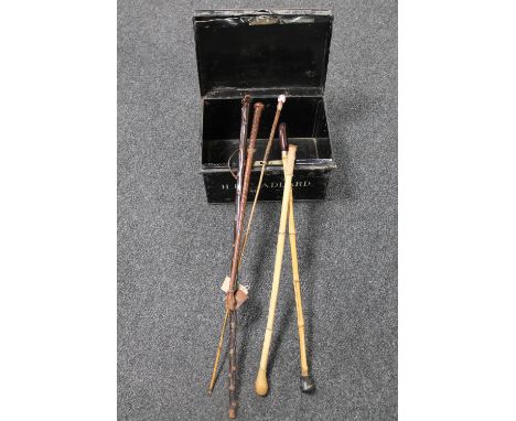 An early 20th century metal deed box containing a swagger stick, two walking sticks and two horse whips