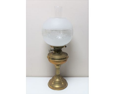 An antique brass oil lamp with glass chimney and shade 