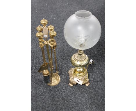 A four-piece brass companion set on stand together with an ornate brass table lamp with glass shade 