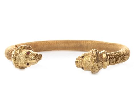GEM SET TORC BANGLE, each terminal set with a lion's head motif, with red cabochon eyes, 70mm to outer edge, unmarked, 20g