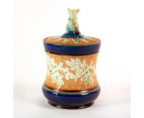 Textured ground with applied floral decor. Lid with stylized mouse finial modeled with a smoking pipe. Impressed Doulton Lamb
