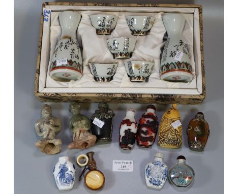 Box comprising Oriental porcelain glass and other snuff bottles with stoppers, carved figures etc.  together with a cased Sak