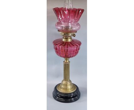 Early 20th century double oil burner lamp having cranberry glass shade above a cranberry glass reservoir standing fluted bras