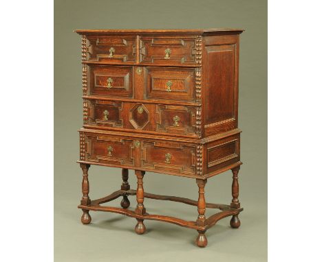 A Carolean style oak chest on stand, early 20th century, with two short drawers above three long drawers, each with cast bras