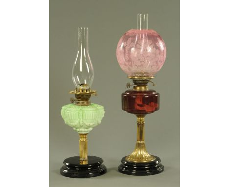 Two Victorian oil lamps, one with a facet etched cranberry glass shade and cranberry reservoir on a brass column, the other w