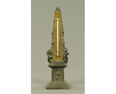 A French spelter desk thermometer, late 19th century, cast as an obelisk, decorated in relief with war trophies, cherubs, wit