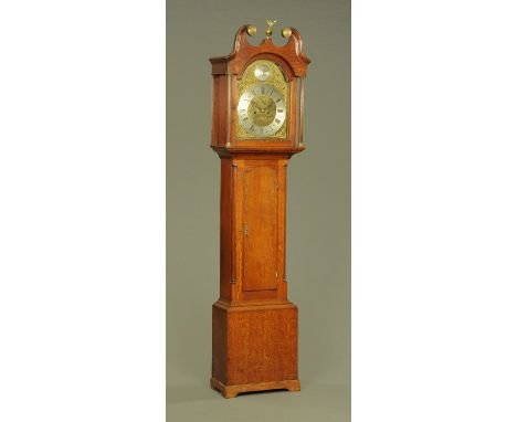 A Georgian oak longcase clock, with arched brass dial and two train striking movement with long trunk door flanked by fluted 